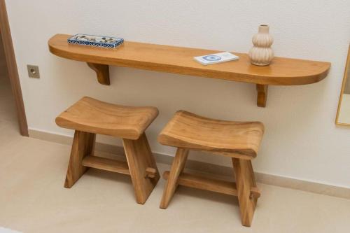 two wooden stools sitting under a wooden shelf on a wall at Ionian Blue Luxury Apartment in Marathopolis
