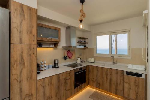 a kitchen with wooden cabinets and a window at Ionian Blue Luxury Apartment in Marathopolis