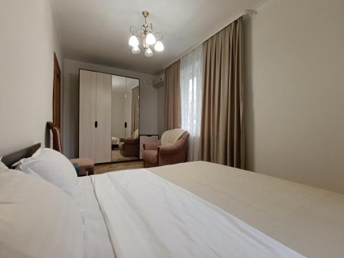 een slaapkamer met een wit bed en een woonkamer bij AURA on Tynystanova street 199 in Bisjkek