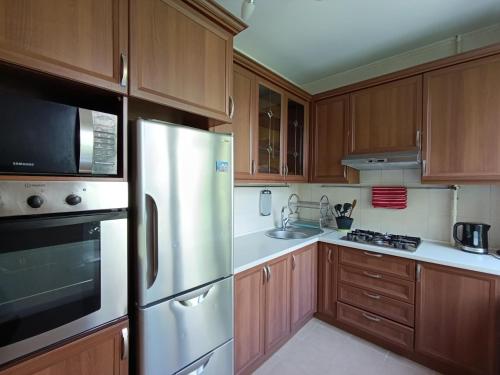 een keuken met houten kasten en een roestvrijstalen koelkast bij AURA on Tynystanova street 199 in Bisjkek