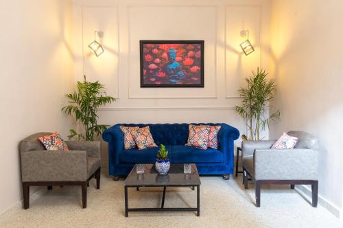 a living room with a blue couch and two chairs at Ved A Boutique Stay in Jaipur