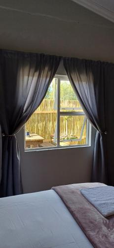 a bedroom with a window with a view of a deck at Winemaker's Rest in Oudtshoorn