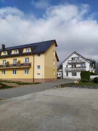 a yellow building with a black roof next to a white building at Penzion U Jandů in Běhařov