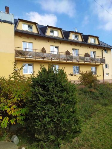 a yellow building with a black roof on a hill at Penzion U Jandů in Běhařov