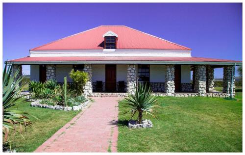 a white house with a red roof and a brick pathway at Thali Thali Game Lodge in Langebaan