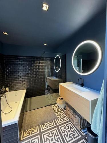 une salle de bain avec une baignoire, un lavabo et un miroir dans l'établissement Maison d'architecte avec piscine-spa chauffé en centre ville de Vaison-la-Romaine, à Vaison-la-Romaine