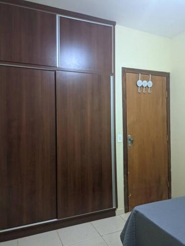 a large wooden closet with a wooden door in a room at Quarto de Casal Bem Localizado Em apto Compartilhado AP 204 in Uberaba