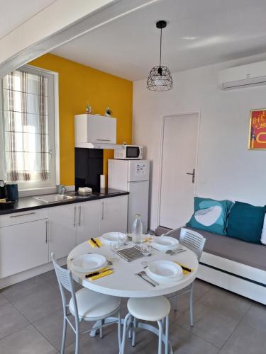- une cuisine avec une table et des chaises blanches dans la chambre dans l'établissement Hébergements Narbonne centre - Local vélos et motos, à Narbonne