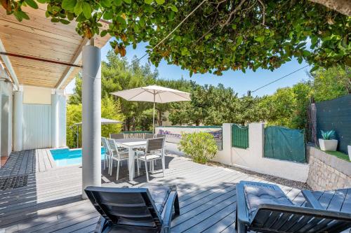 un patio avec une table, des chaises et un parasol dans l'établissement L'Aigade Villa 4* à Fontsainte, à La Ciotat