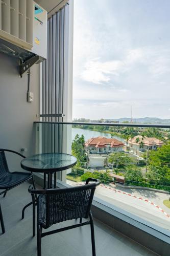 a balcony with a table and chairs and a large window at Laguna Lakeside apartments with panoramic view in Bang Tao Beach