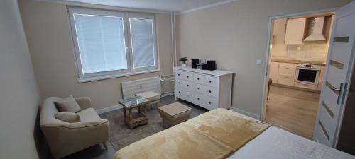 a bedroom with a bed and a chair and a dresser at Apartmán pri hrade in Levice