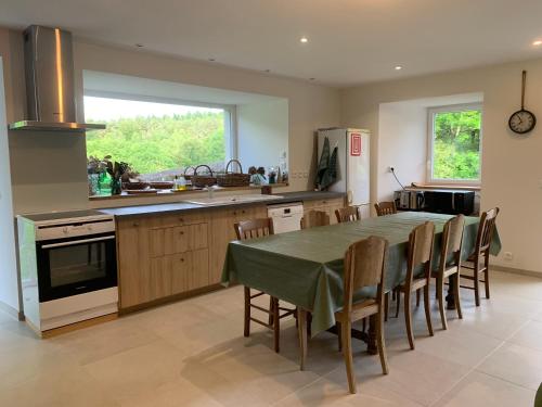 une cuisine avec une table et des chaises dans une cuisine dans l'établissement Ferme au calme à 15mn du Chambon sur Lignon, à Saint-Jeures