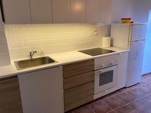 a kitchen with a sink and a white refrigerator at La Casita Turquesa in Almuñécar