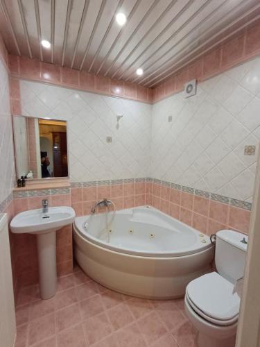 a bathroom with a tub and a toilet and a sink at Penelope Apartment Hotel in Dassia