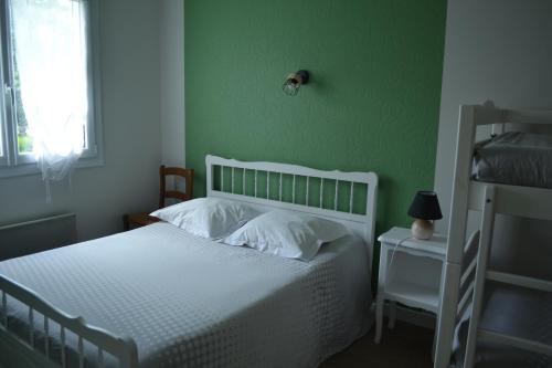 a bedroom with a white bed and a green wall at Chambre d'hôtes la ville en bois in Mouchamps