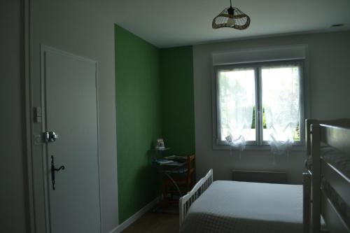 - une chambre avec des murs verts, un lit et une fenêtre dans l'établissement Chambre d'hôtes la ville en bois, à Mouchamps