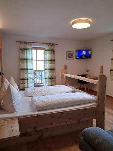 a bedroom with two beds and a tv on the wall at Schweiggerhof -Agriturismo- Farm Holidays in Villandro