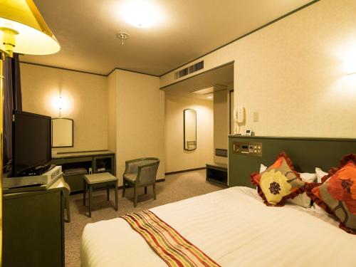 東広島市にあるホテルエリアワン広島ウイングのベッド、デスク、テレビが備わるホテルルームです。