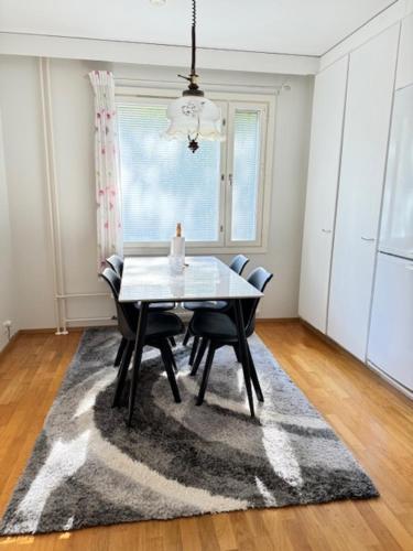 a dining room with a table and chairs on a rug at Ilona Apartment, ESCAPE 2 in Kotka