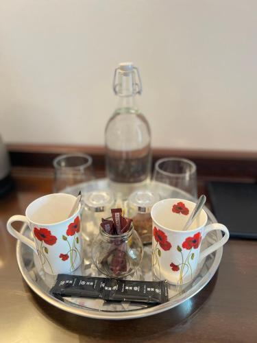 a tray with two cups and a bottle on a table at Chez Thomas 7 Route du Monde Ancien in Saint-Georges-dʼAunay