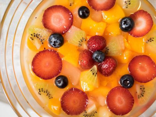 a bowl of fruit with kiwi oranges strawberries and blueberries at Hotel Areaone Hiroshima Wing in Higashihiroshima