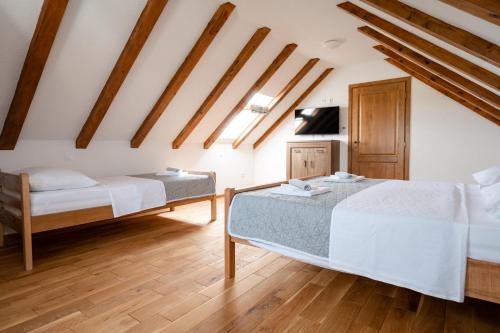 two beds in a room with wooden ceilings at Didova kuća, kamena vila sa bazenom u blizini Rogoznice in Podorljak