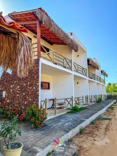a white building with a thatched roof at Pousada Curva dos Ventos in Icaraí