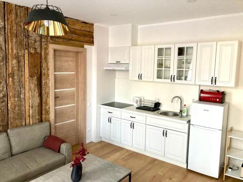una cocina con armarios blancos y un sofá en una habitación en Tikrai nelis, en Liepāja