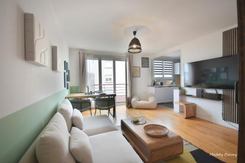 a living room with a white couch and a table at Logement 3 chambres, proche centre ville, parking gratuit in Vannes