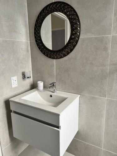 a bathroom with a white sink and a mirror at Sweet Daisies Apartment in Mbabane
