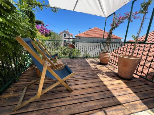 a wooden deck with a chair and an umbrella at Eco Chalet Style Apartment in Sutivan