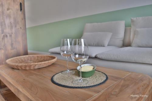 two wine glasses and a bowl on a wooden table at Logement 3 chambres, proche centre ville, parking gratuit in Vannes