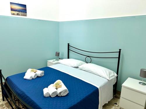a blue bedroom with a bed with towels on it at Brezza Marina Apartments in Giardini Naxos