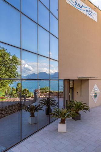 a building with large glass windows and plants in front at Wind Hotel in Malcesine