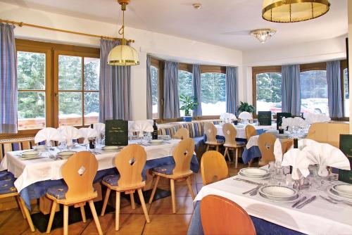 a dining room with tables and chairs and windows at Hotel Villetta Maria Cottage in Canazei