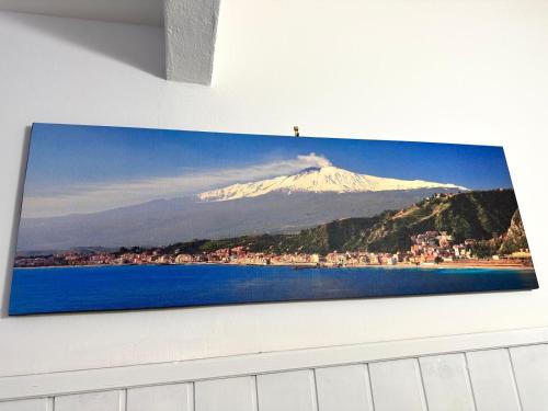 a picture of a snow covered mountain hanging on a wall at Brezza Marina Apartments in Giardini Naxos