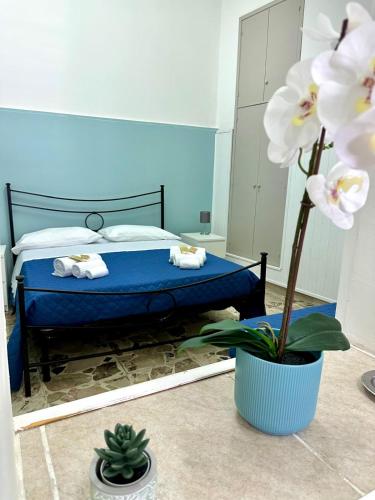 a bedroom with a blue bed and a potted plant at Brezza Marina Apartments in Giardini Naxos