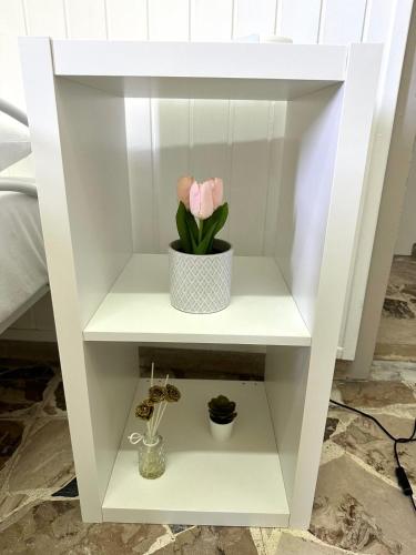 a white shelf with a pink flower in it at Brezza Marina Apartments in Giardini Naxos
