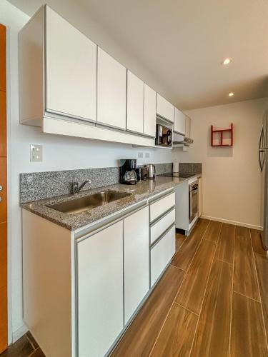 a kitchen with white cabinets and a wooden floor at Turek Residences in Ushuaia