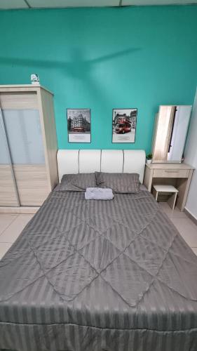 a large bed in a room with a blue wall at MAR Homestay Seri Iskandar in Seri Iskandar