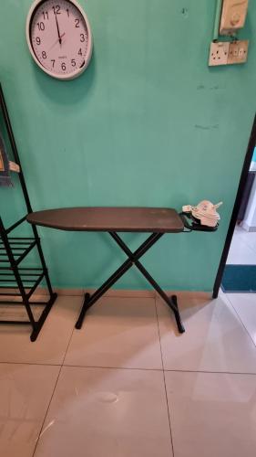 a clock on a wall next to a table at MAR Homestay Seri Iskandar in Seri Iskandar