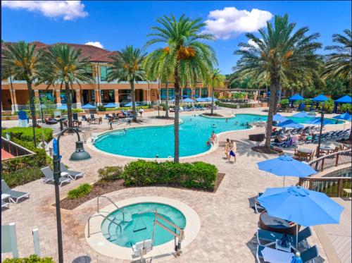 a pool at a resort with palm trees and umbrellas at Camaro in Orlando