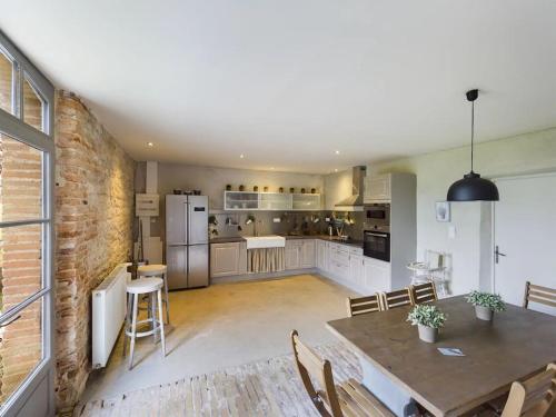 a large kitchen with a table and a brick wall at Manoir des Barrayrous in Nègrepelisse