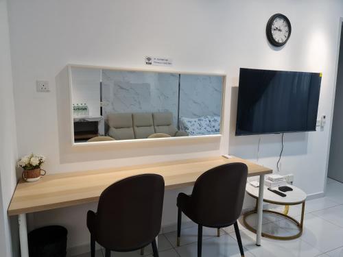 a room with a desk with chairs and a television at Sky Trees Apartment at Bukit Indah Johor in Johor Bahru