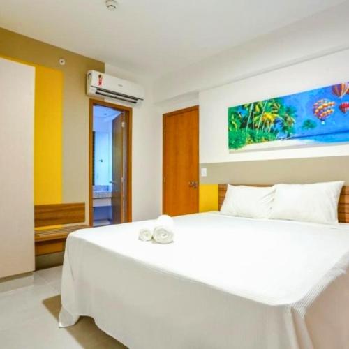 a bedroom with a large white bed with a painting on the wall at Resort em Olimpia in Olímpia