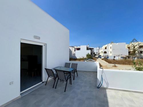 a balcony with a table and chairs on a white wall at Anemos Naxos town suites-apartment in Naxos Chora