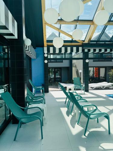 a row of green chairs and tables in a building at Morze Niechorze Domy całoroczne in Niechorze