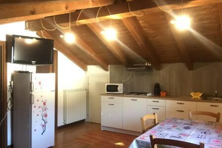 a kitchen with a refrigerator and a table with chairs at Casa Grazia in Magreglio