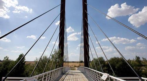 a suspension bridge with a blue sky and clouds at Hotel Comendador in Carranque
