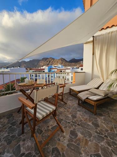 a patio with chairs and a table on a balcony at Sunset Oasis of Los Gigantes in Puerto de Santiago